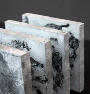 The material studies are composed of cement and wax. Through a process of quickly cooling, hot wax hardens into organic shapes in cold water. Later, the wax is cast in hardening cement cubes. These fragile cubes of cement are then segmented and extruded into slides. Finally, the wax is later melted out to finish the reciprocal process.